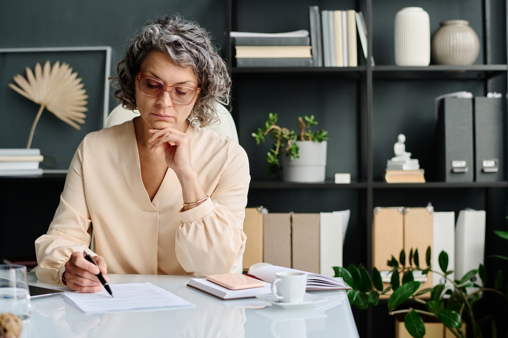 Serious,female,auditor,or,analyst,with,pen,looking,through,financial